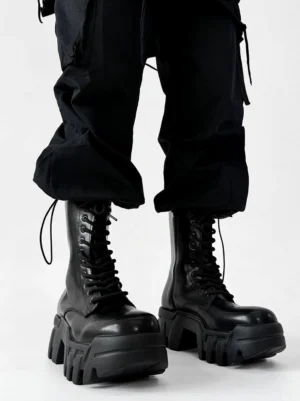 Front low angle view of black futuristic zip platform combat boots with chunky lug soles and black cargo pants