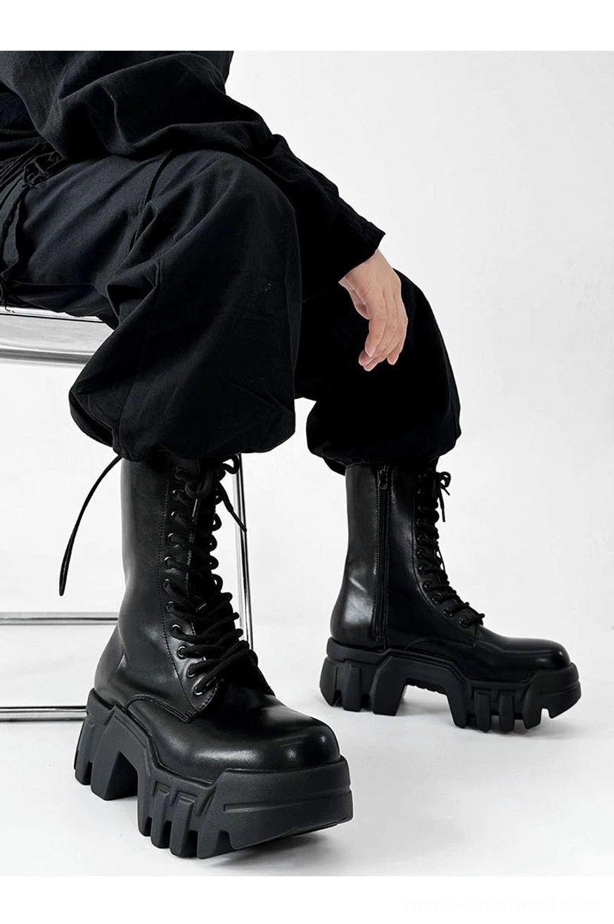 Three quarter view of black platform combat boots with glossy upper lug tread and rolled cargo pants