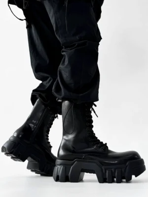 Side three quarter view of black futuristic platform combat boots with lace up closure and thick block heel soles