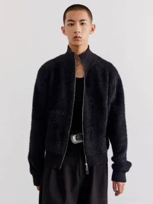 Close-up front view of black fuzzy fleece zip cardigan showing silver zipper stand collar and ribbed hem