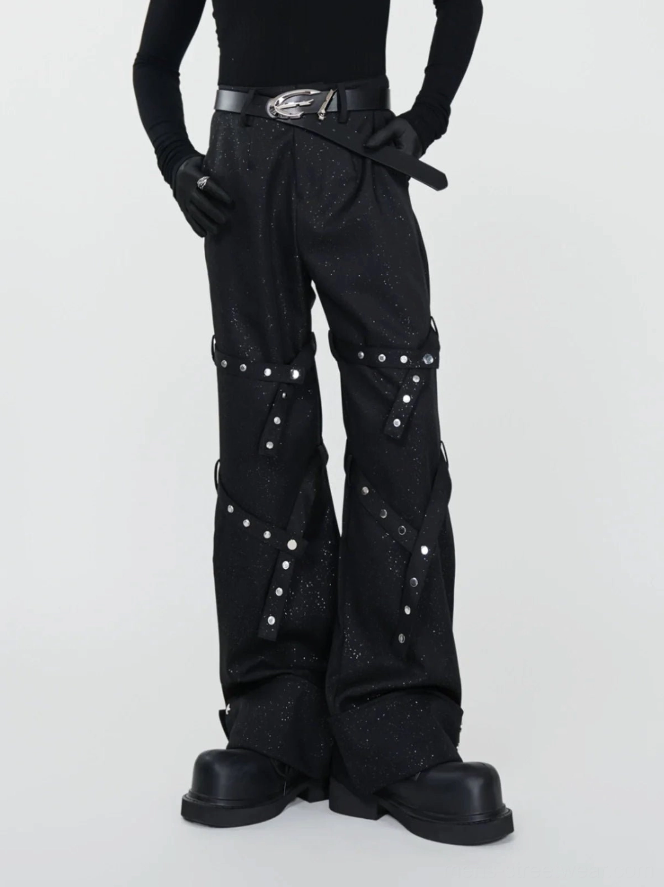 Three quarter front view of black glitter flare pants with silver rivet straps leather belt gloves and platform boots