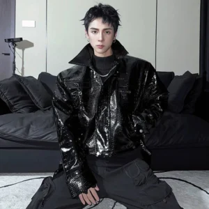 Black glossy crocodile embossed faux leather moto jacket worn by male model in a front three-quarter streetwear portrait