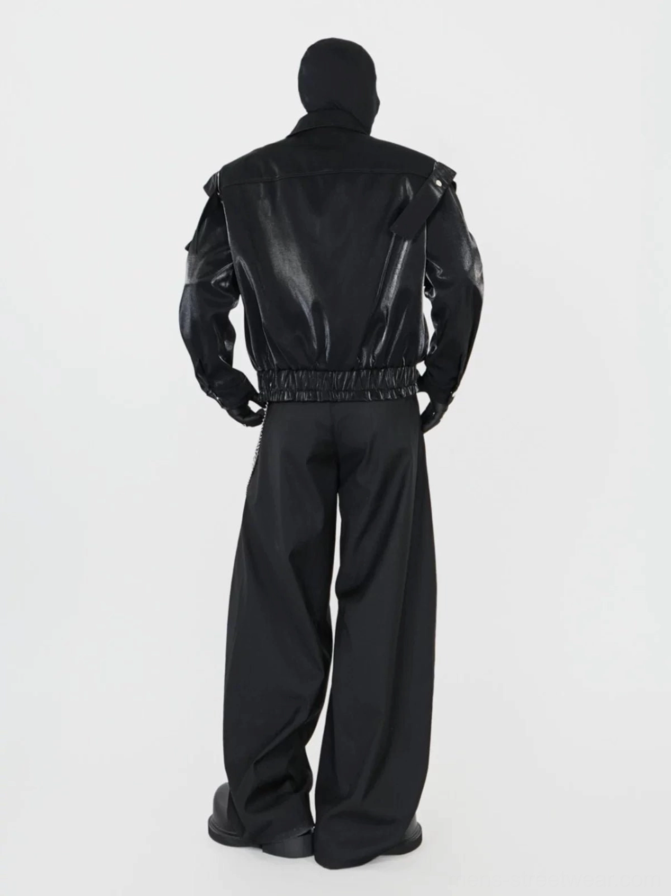 Rear view of a black glossy faux leather biker jacket showing the patent back panel, elastic ruched hem, and layered cyberpunk outfit