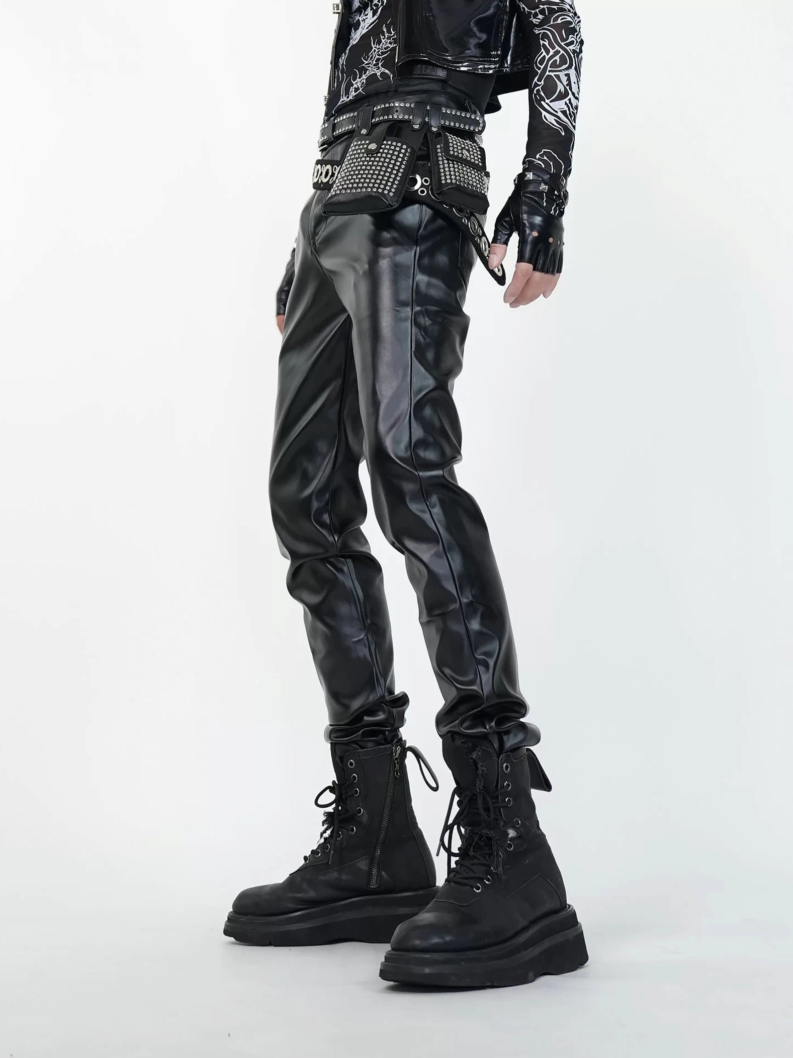 Left side view of black glossy faux leather combat pants with slim leg silhouette and platform combat boots