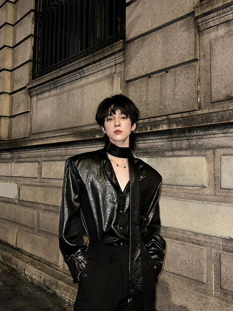 Black glossy tie-neck shirt with deep V neckline, matching tie detail, and relaxed streetwear fit