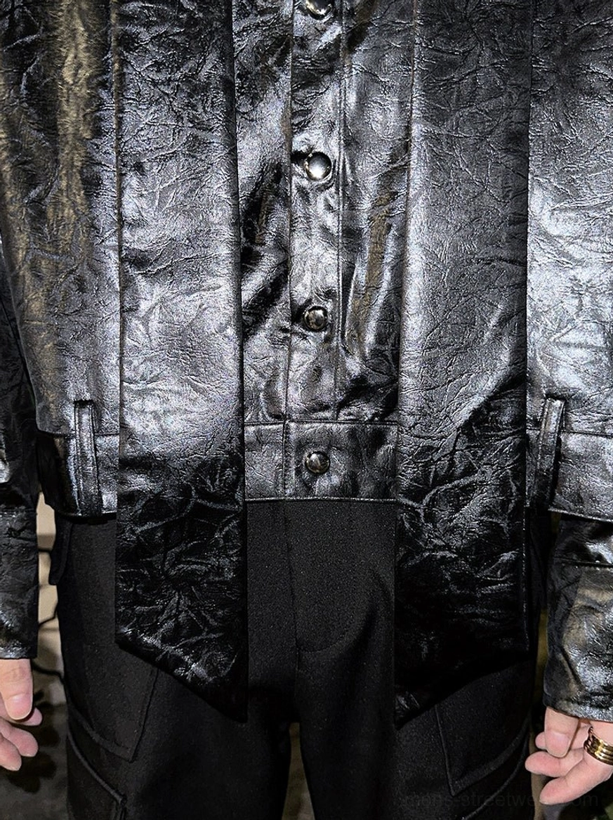 Close-up of relaxed black glossy tie-neck shirt body with textured finish and buttoned front