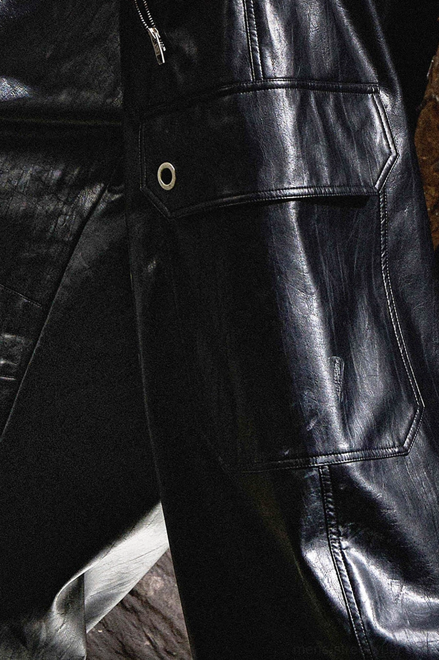 Close-up of black gothic cargo pants flap pocket with snap fastener, stitched seams and smooth leather-look finish