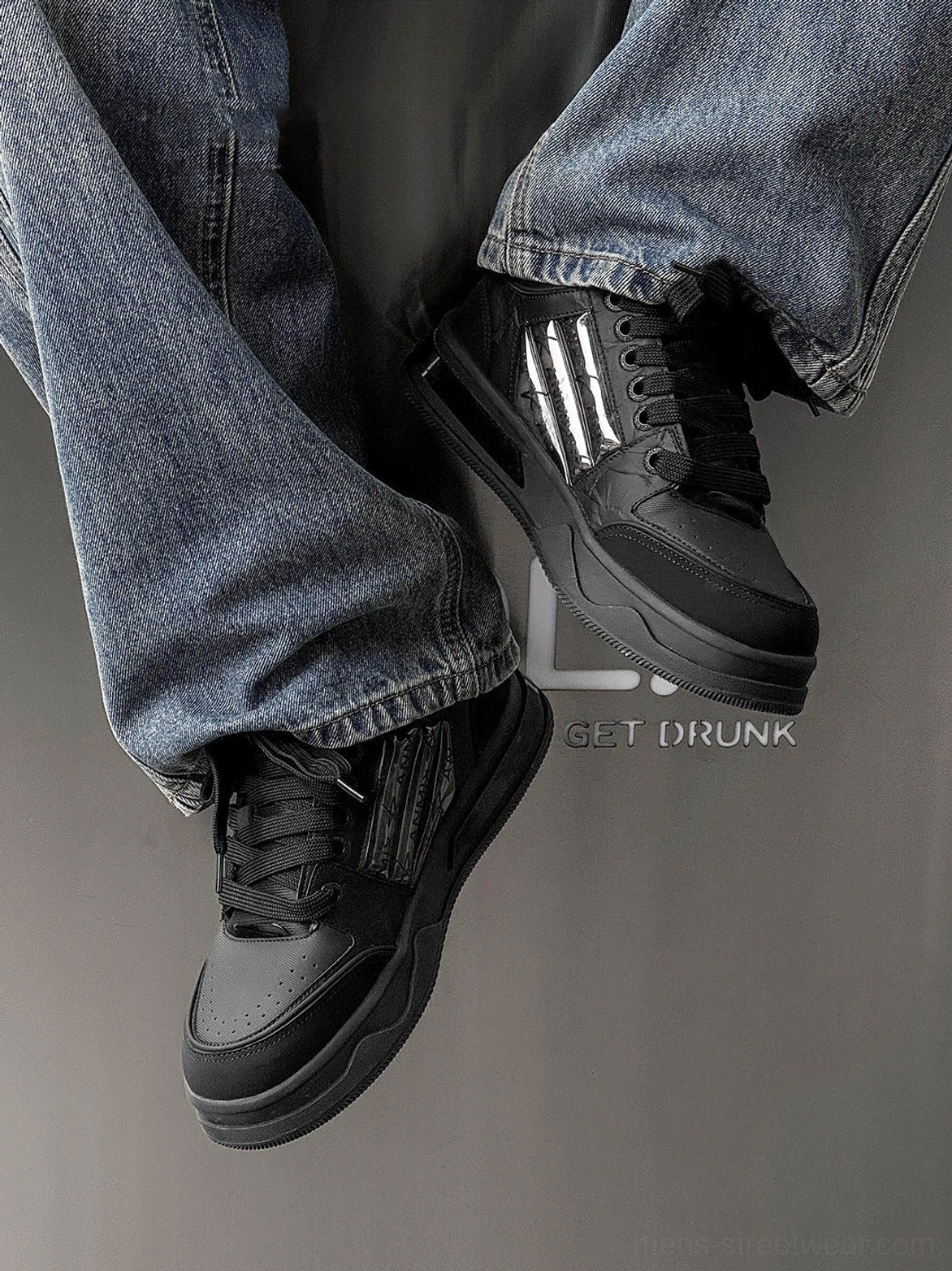 Black gothic casual sneakers with silver striped side panels and thick platform soles paired with relaxed blue streetwear denim