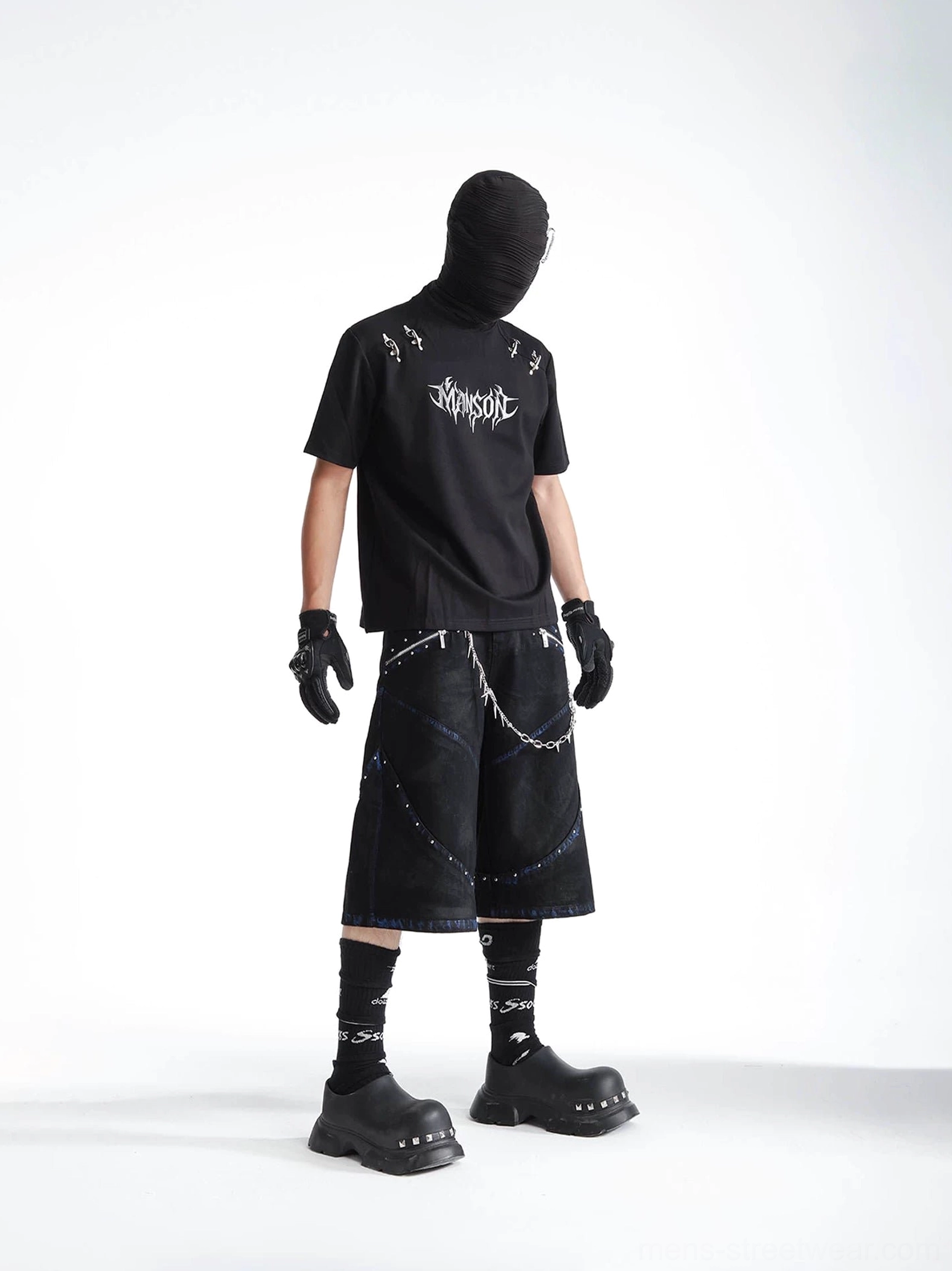 Side view of a black gothic punk T-shirt styled with baggy denim shorts, chain belt, gloves, and chunky platform boots