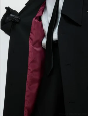 Close-up of black gothic trench coat open front with burgundy red satin lining metal buttons white shirt and black tie