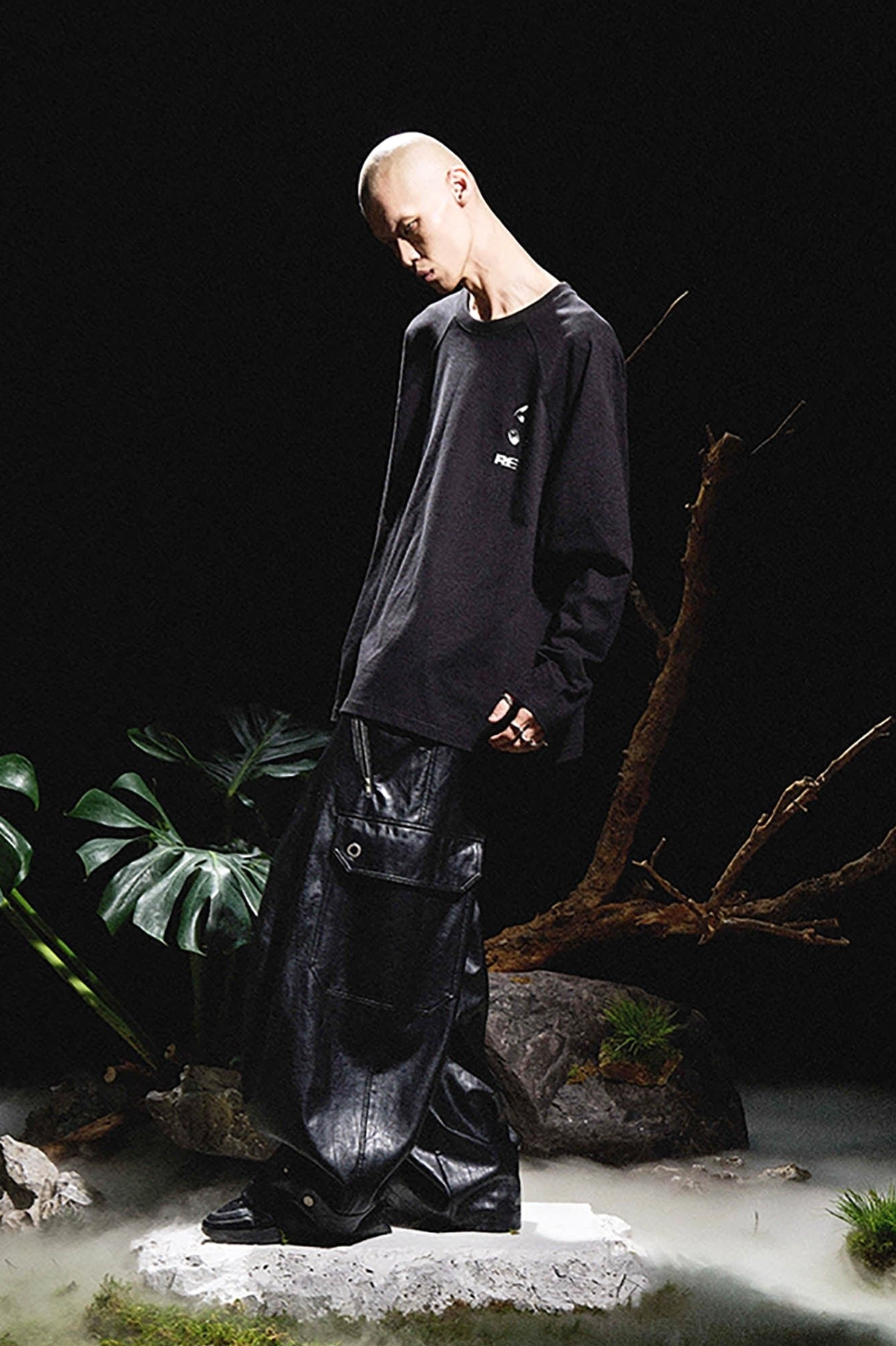 Full side profile of black gothic wide-leg cargo pants styled with a black long-sleeve streetwear top