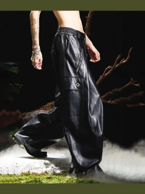 Rear low-angle view of black gothic wide-leg faux leather cargo pants with oversized legs, utility pocket and stacked hem