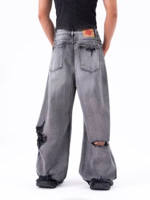 Rear view of black and gray distressed wide-leg jeans showing classic back pockets, leather waist patch, and subtle lower-leg ripping