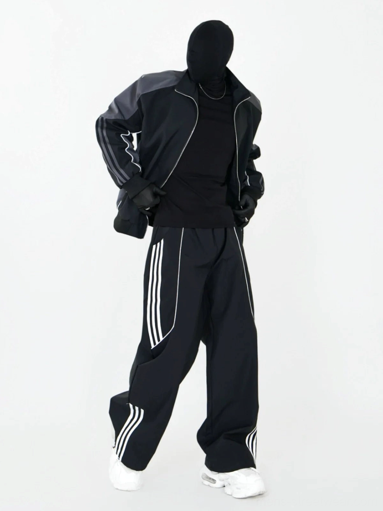 Black and dark gray coordinated streetwear outfit featuring wide-leg triple-stripe track pants and matching zip-up athletic jacket