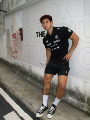 Men wearing a black Great Vibes graphic polo shirt with black shorts white socks and canvas sneakers in a modern streetwear outfit