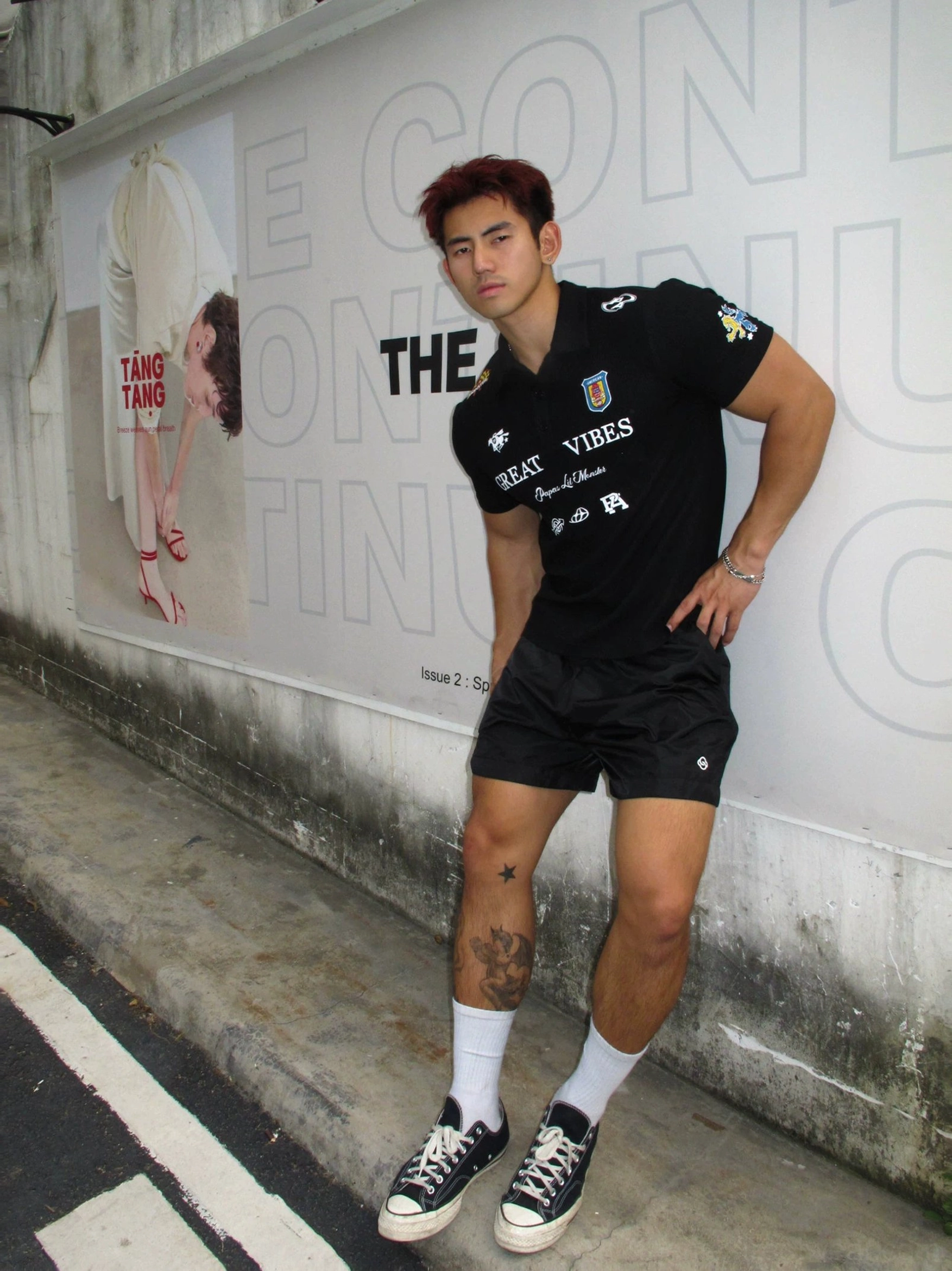 Men wearing a black Great Vibes graphic polo shirt with black shorts white socks and canvas sneakers in a modern streetwear outfit