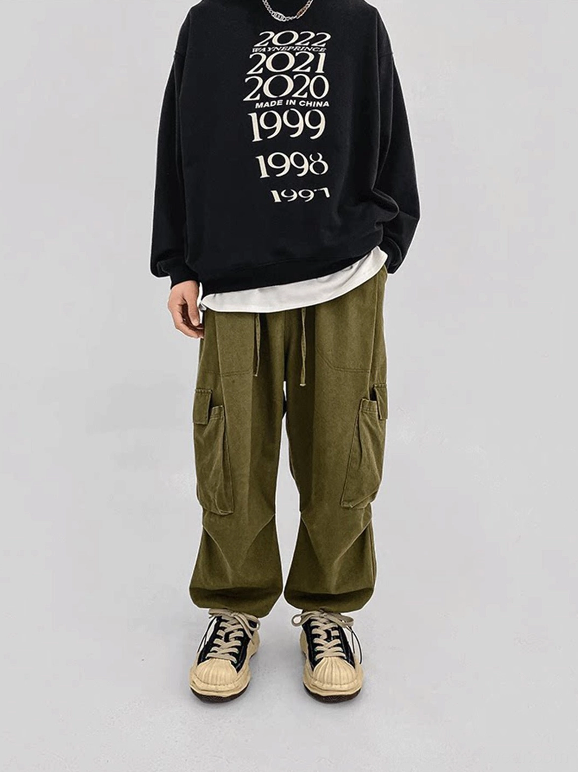 Black and green dissolving-sole platform sneakers worn with a graphic sweatshirt and olive cargo pants in a streetwear outfit