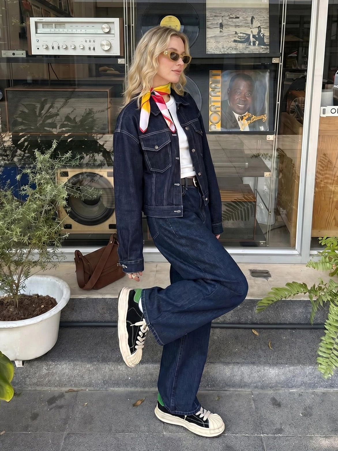 Black and green shell-toe platform sneakers styled with a denim streetwear outfit near a retro shop entrance