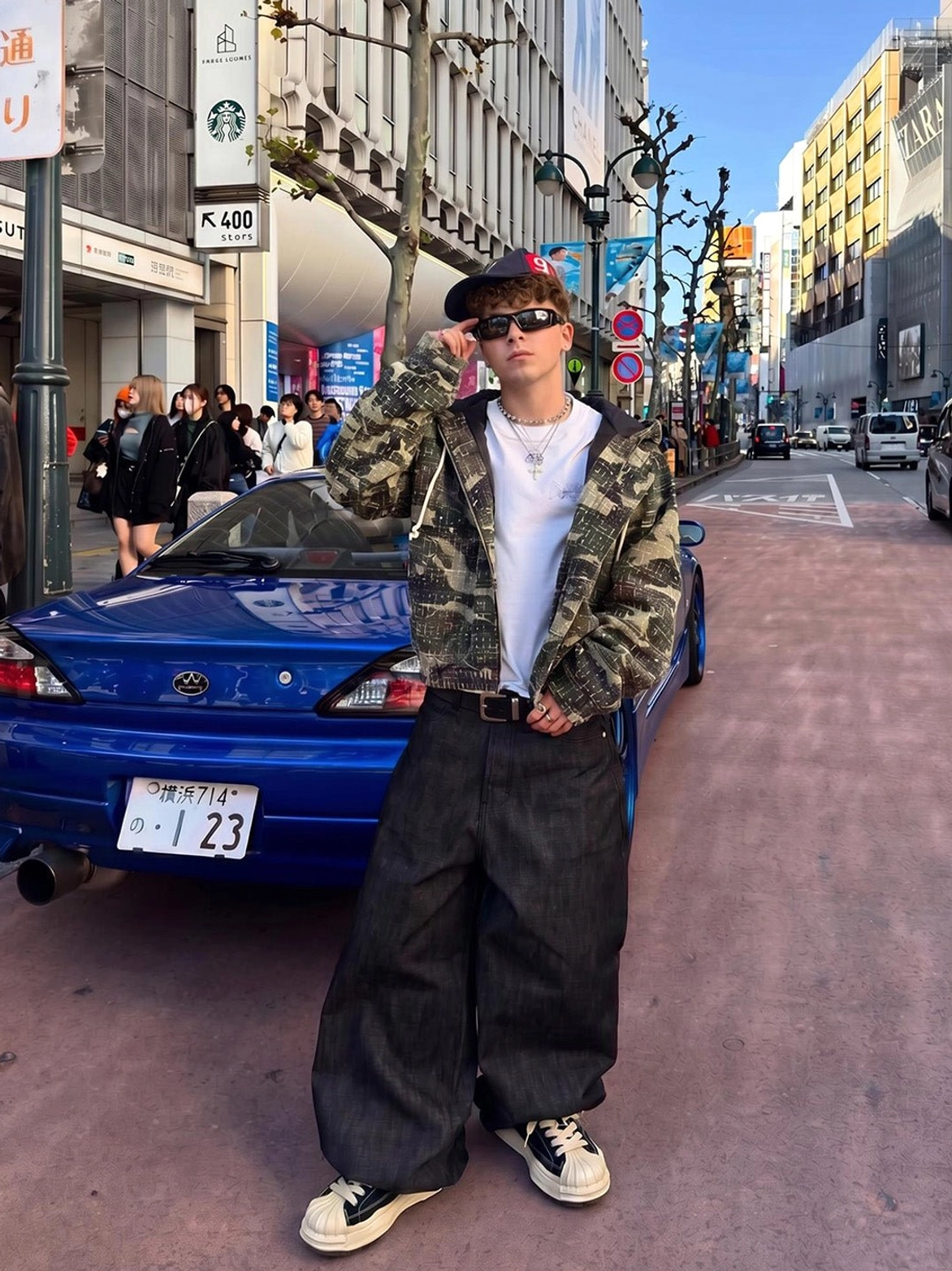 Black and green shell-toe platform casual sneakers worn with a camo jacket and baggy denim in a Japanese-inspired urban street setting