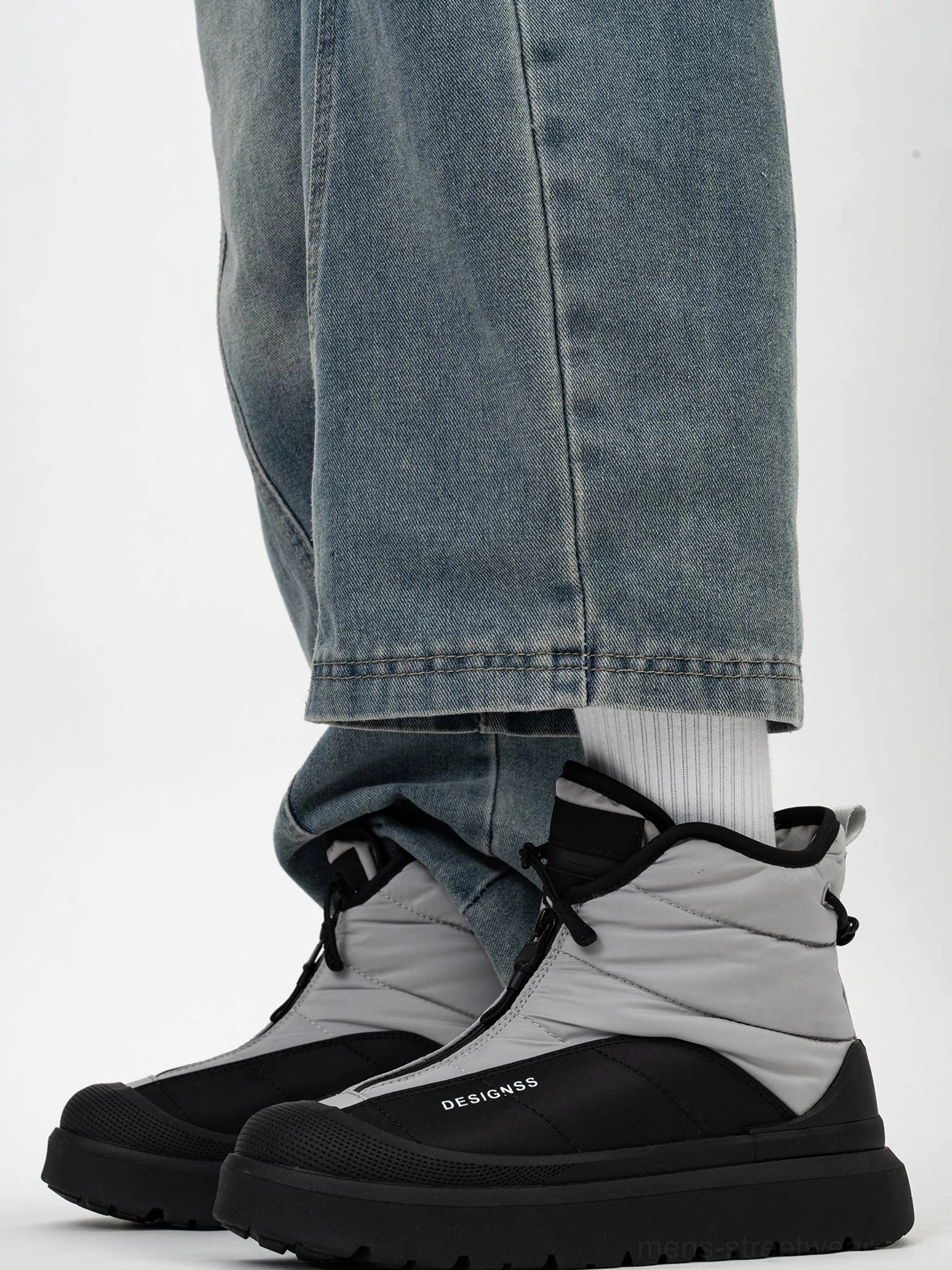Pair of black and grey fleece-lined snow boots shown from the front with contrast toe caps, chunky platform soles, and casual streetwear jeans