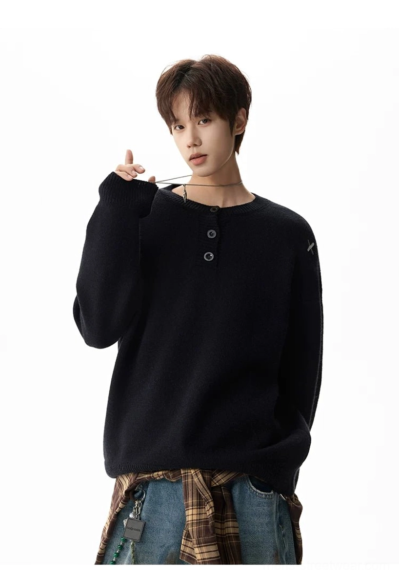 Close front view of a black henley knit sweater with smooth knit texture, button placket, and subtle cross shoulder embroidery