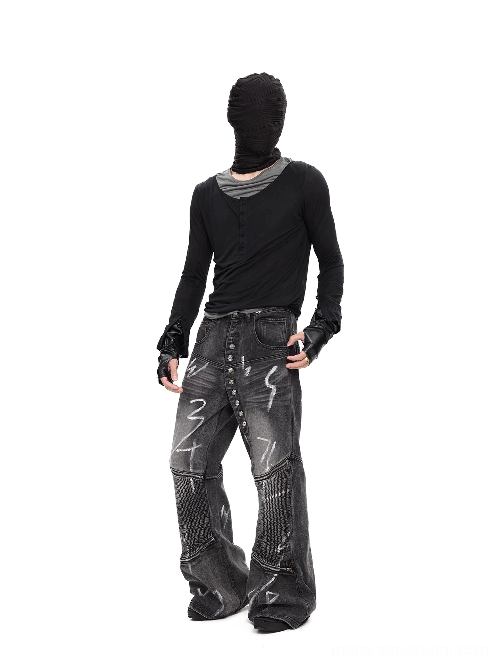 Full dark streetwear outfit featuring a black layered Henley top, wide-leg graffiti print jeans, fingerless leather gloves, and avant-garde styling