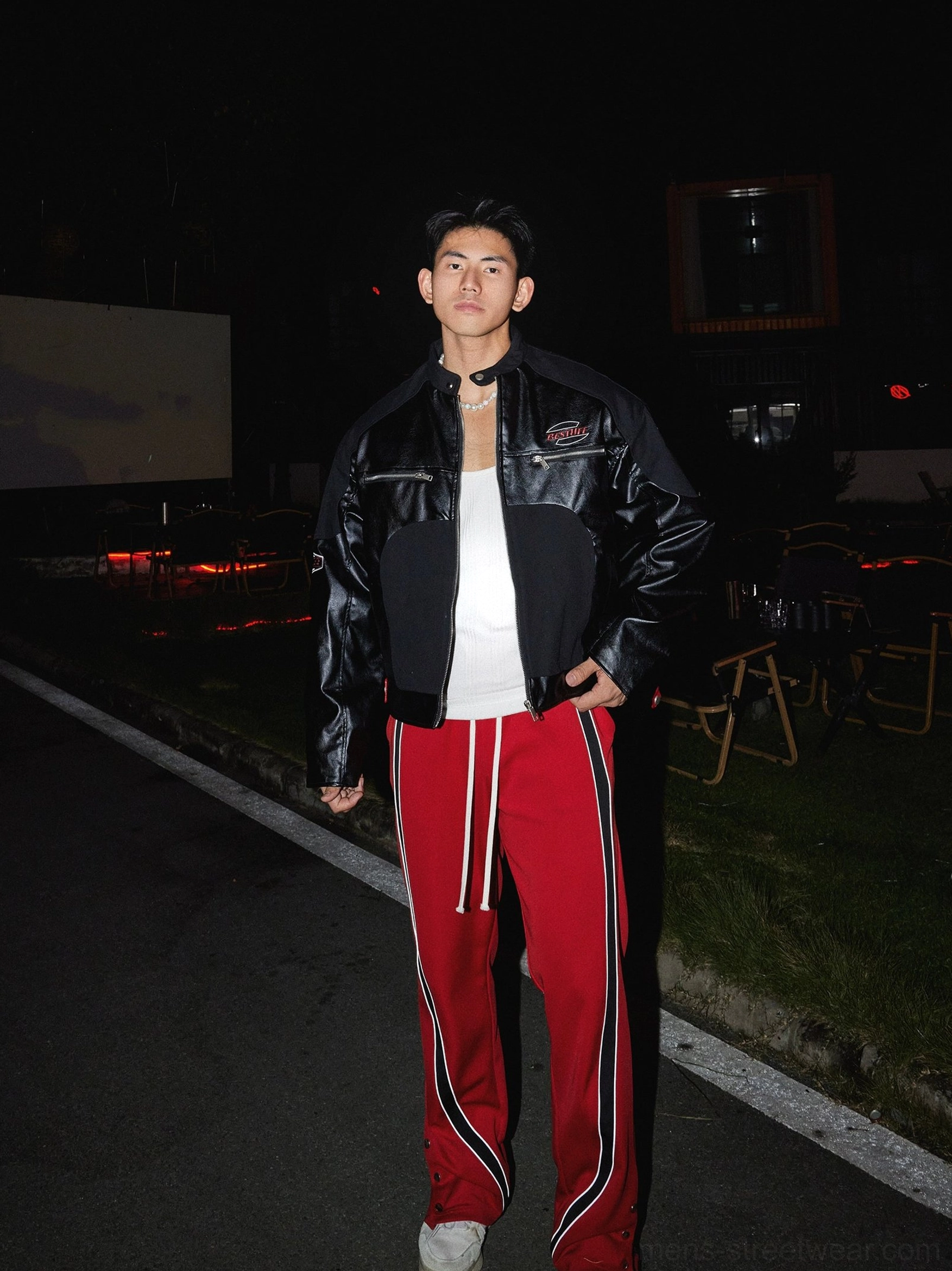 Black high collar racing zip-up winter streetwear jacket full body side view styled with red striped track pants