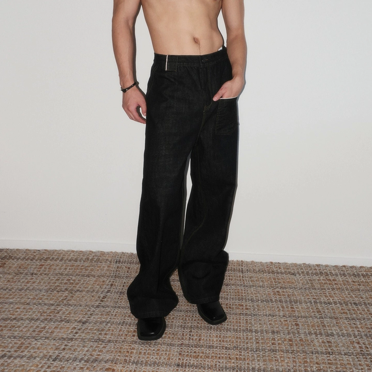 Front full-body view of black high rise baggy wide leg utility jeans with exposed waistband and contrast stitching