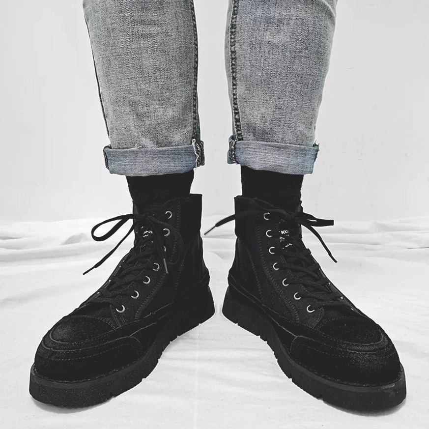 Black high-top work sneakers styled with rolled gray denim and black socks, featuring chunky durable outsole and classic laces
