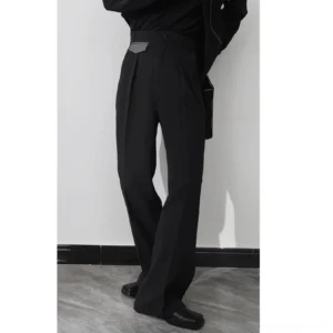 Side view of black high-waist pleated wide-leg tailored trousers styled with black top leather shoes and side bag