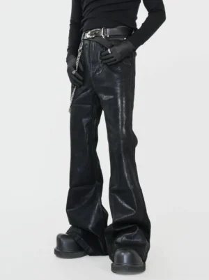 Close-up front view of black faux-leather coated flared jeans showing the high-waisted fit, smooth glossy finish, wide leg, and metal pant chain