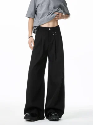 Full front view of black high waisted pleated wide leg trousers showing contrast cross stitch fly detail and tailored drape