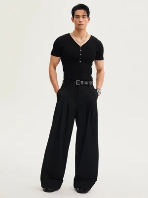 Full-body male model wearing black high-waisted oversized pleated trousers with wide legs, rolled cuffs, leather belt styling, and contemporary Korean fashion look
