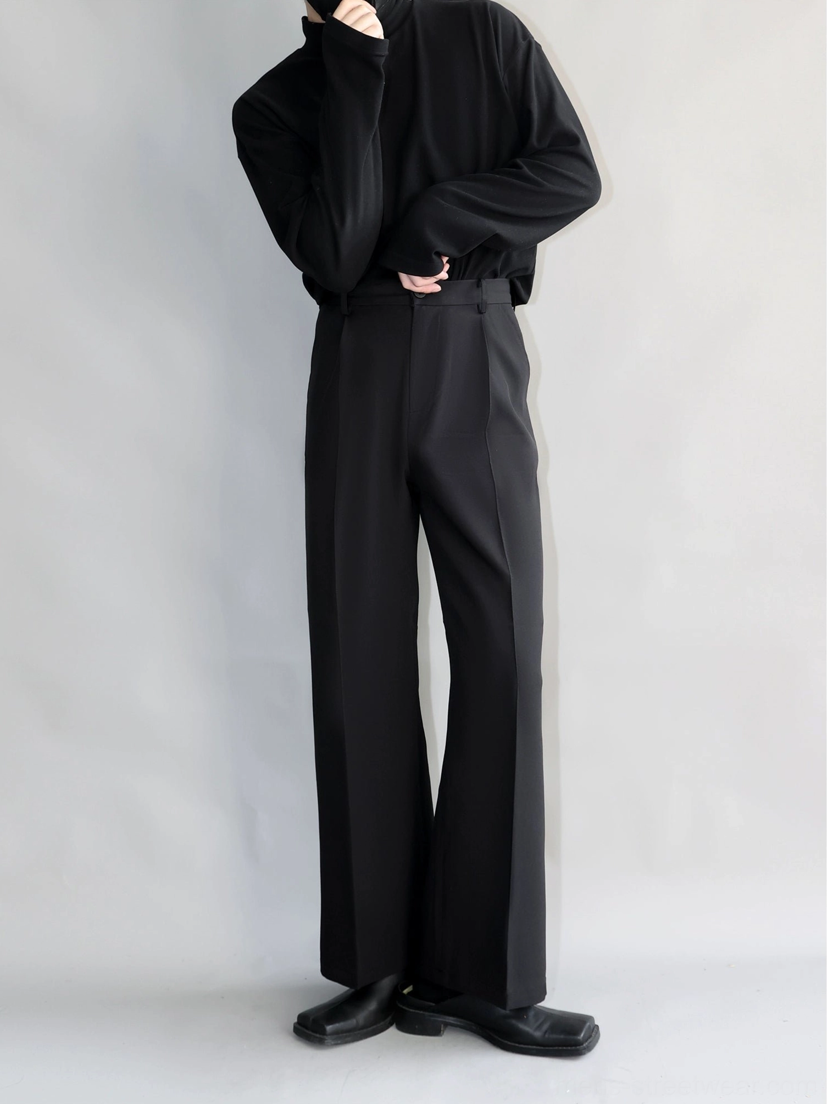 Black high-waisted pleated straight-leg tailored trousers styled in an all-black minimalist streetwear outfit front full-body view