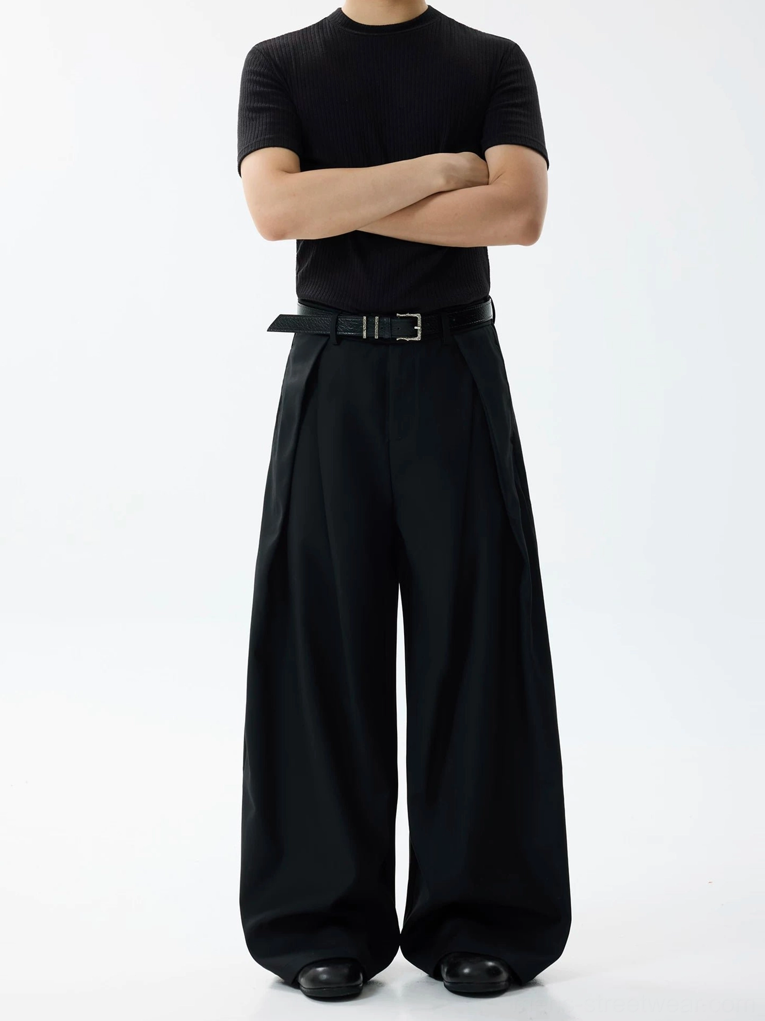 Black high-waisted pleated wide-leg formal trousers with fluid drape styled on a male model