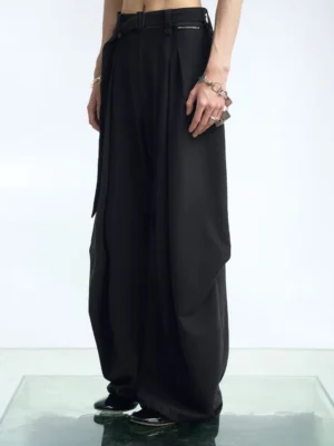 Black high-waisted pleated wide-leg suit pants styled with punk jewelry and a flowing draped silhouette