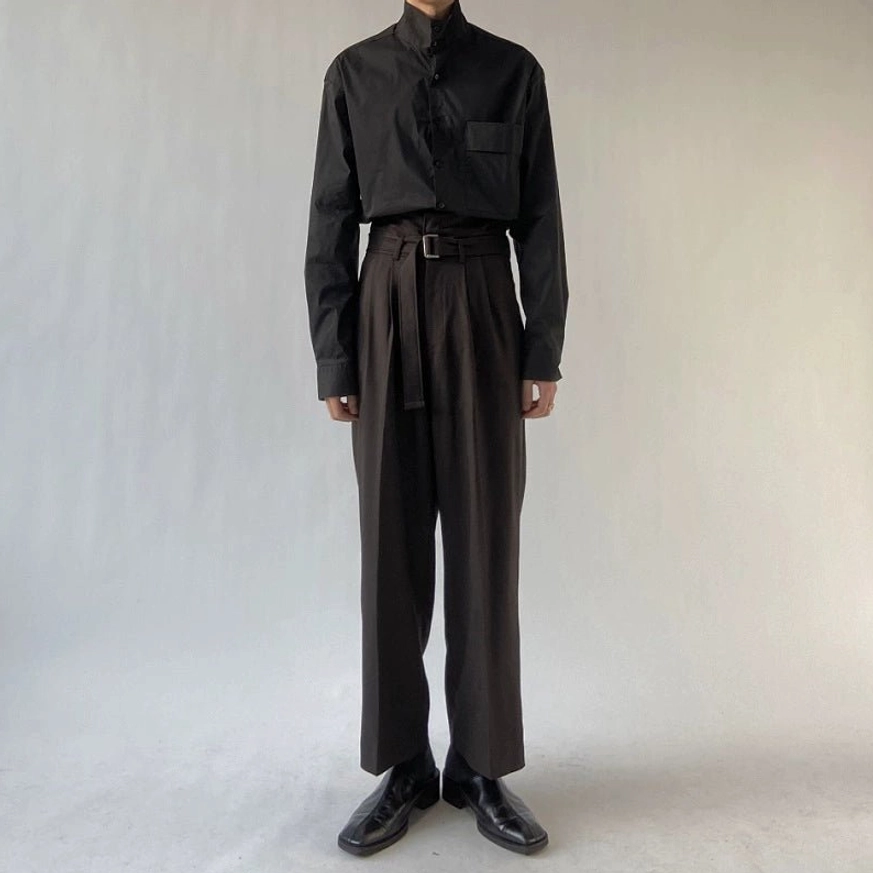Front view of black high-waisted trousers with pleated waist, matching belt, wide-leg fit, and black stand-collar shirt