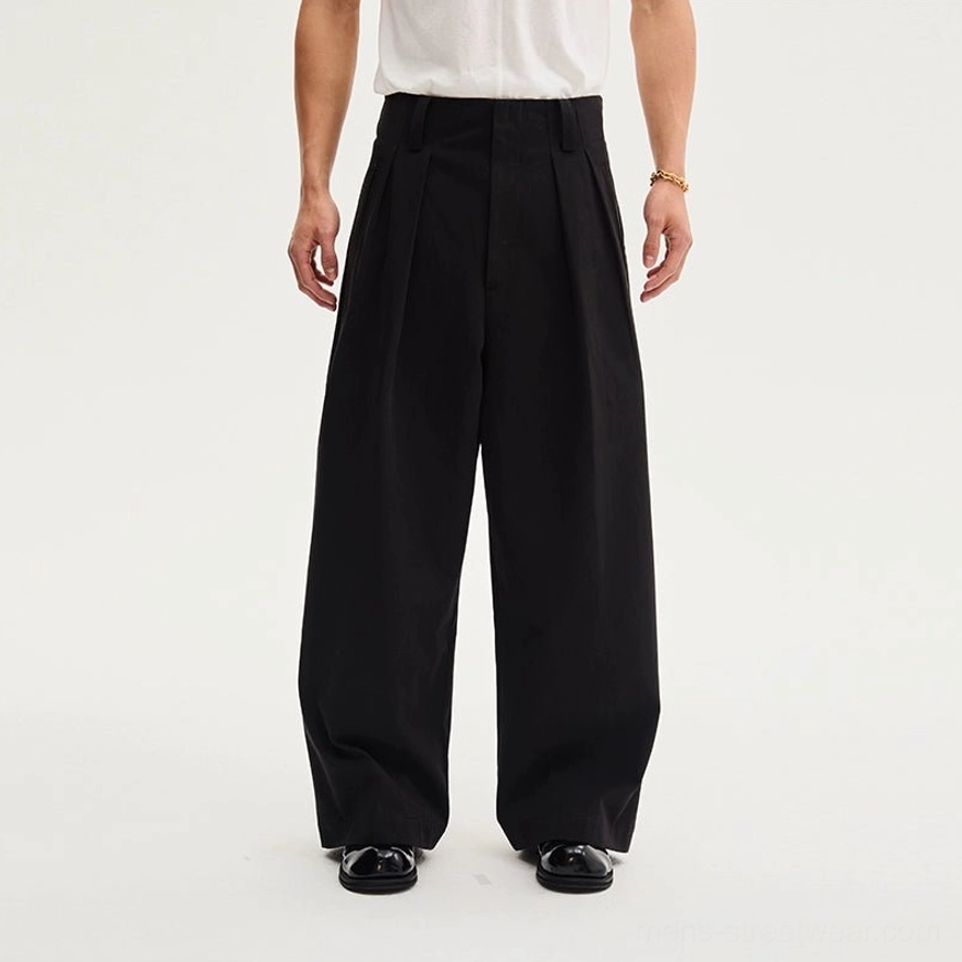 Back lower-body view of black high-waisted tailored wide-leg trousers showing clean seams, relaxed drape, and modern streetwear proportions