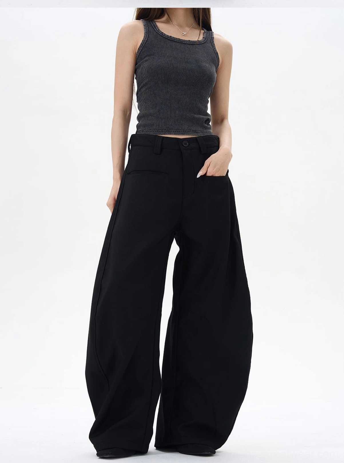 Three-quarter front view of black high-waisted wide-leg pants with side pockets and a curved flowing leg silhouette