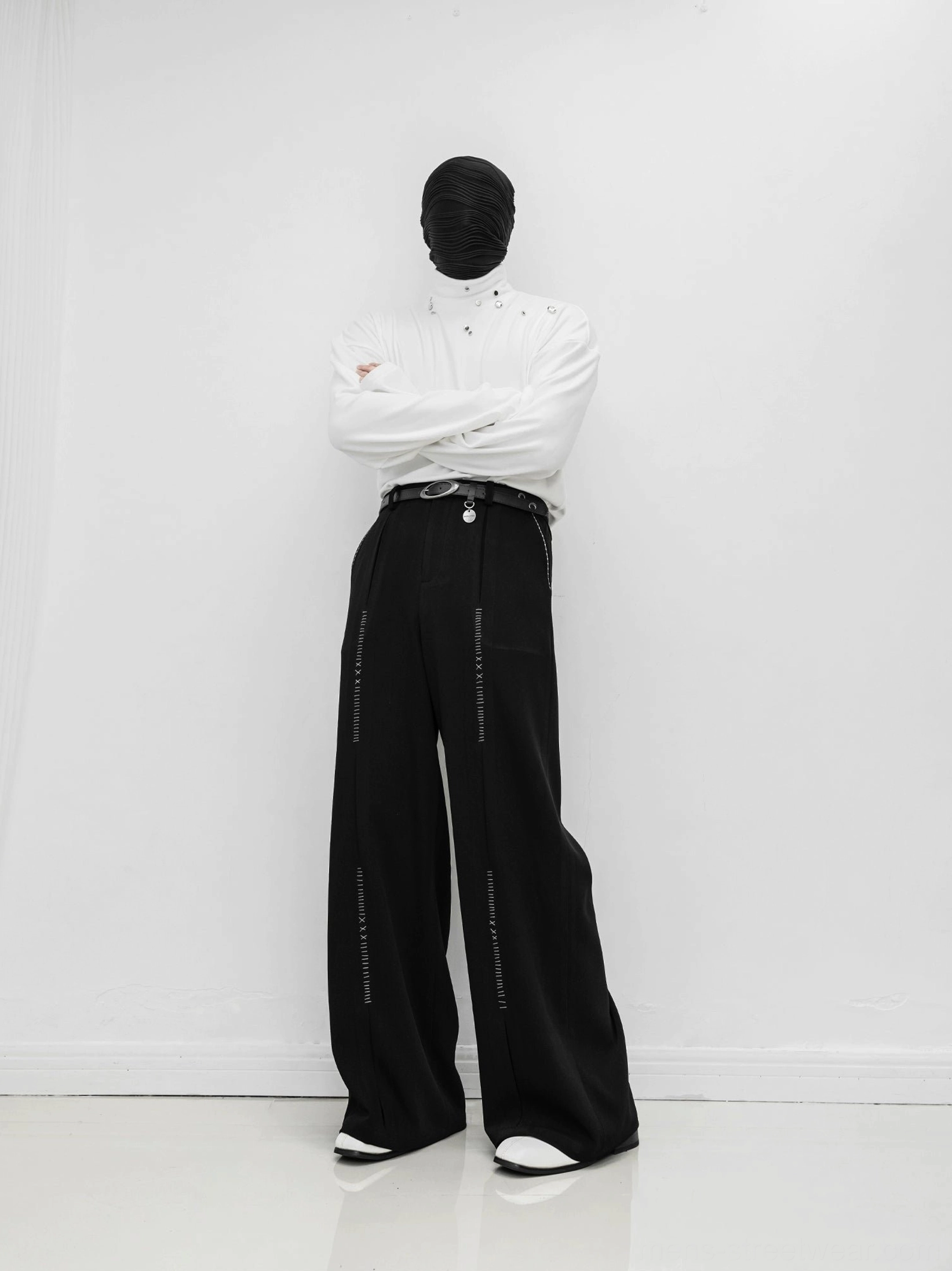 Black high-waisted wide-leg streetwear trousers styled with a white top and black leather belt, featuring decorative vertical stitching