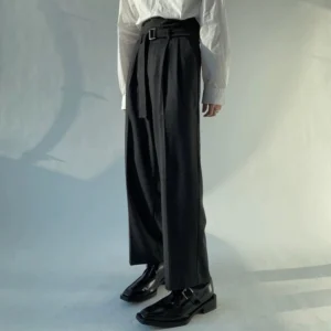 Black high-waisted wide-leg trousers viewed from the right front side with an adjustable fabric belt, relaxed silhouette, and black leather dress shoes