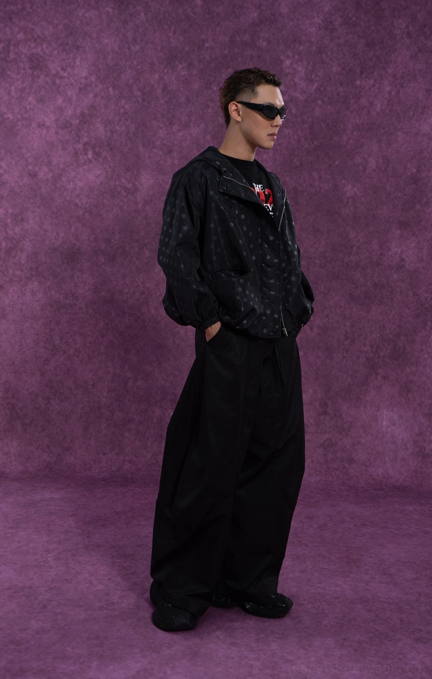 Black hooded polka dot windbreaker jacket left side view styled with wide leg black pants