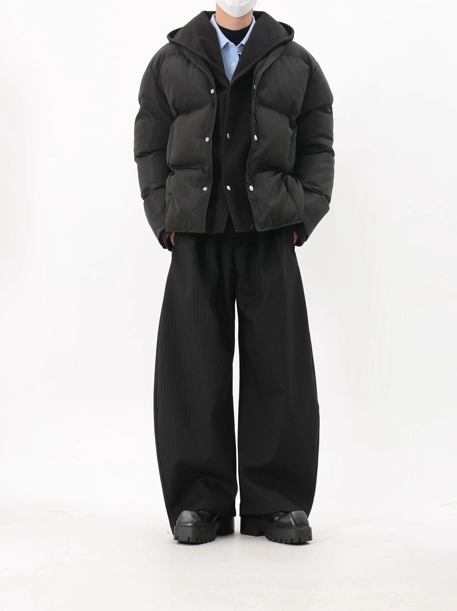 Black hooded snap-button puffer jacket with cropped relaxed silhouette styled with wide-leg black pants