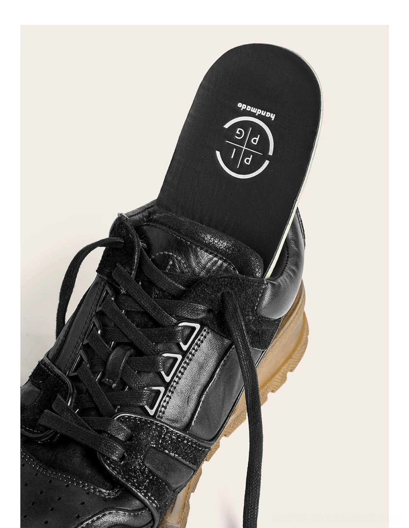 Close-up side view of a black horsehide leather chunky sneaker showing lace hardware, textured upper, and cushioned sole