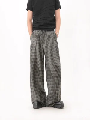 Black houndstooth pleated wide leg pants shown from a low front angle with relaxed oversized Seoul streetwear silhouette