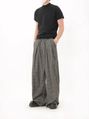 Black houndstooth relaxed wide leg trousers with front pleats side pockets and elasticized waist in a minimalist studio