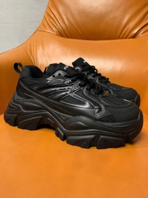 Pair of black chunky platform streetwear sneakers with sculpted elevated soles and heel pull tabs side view