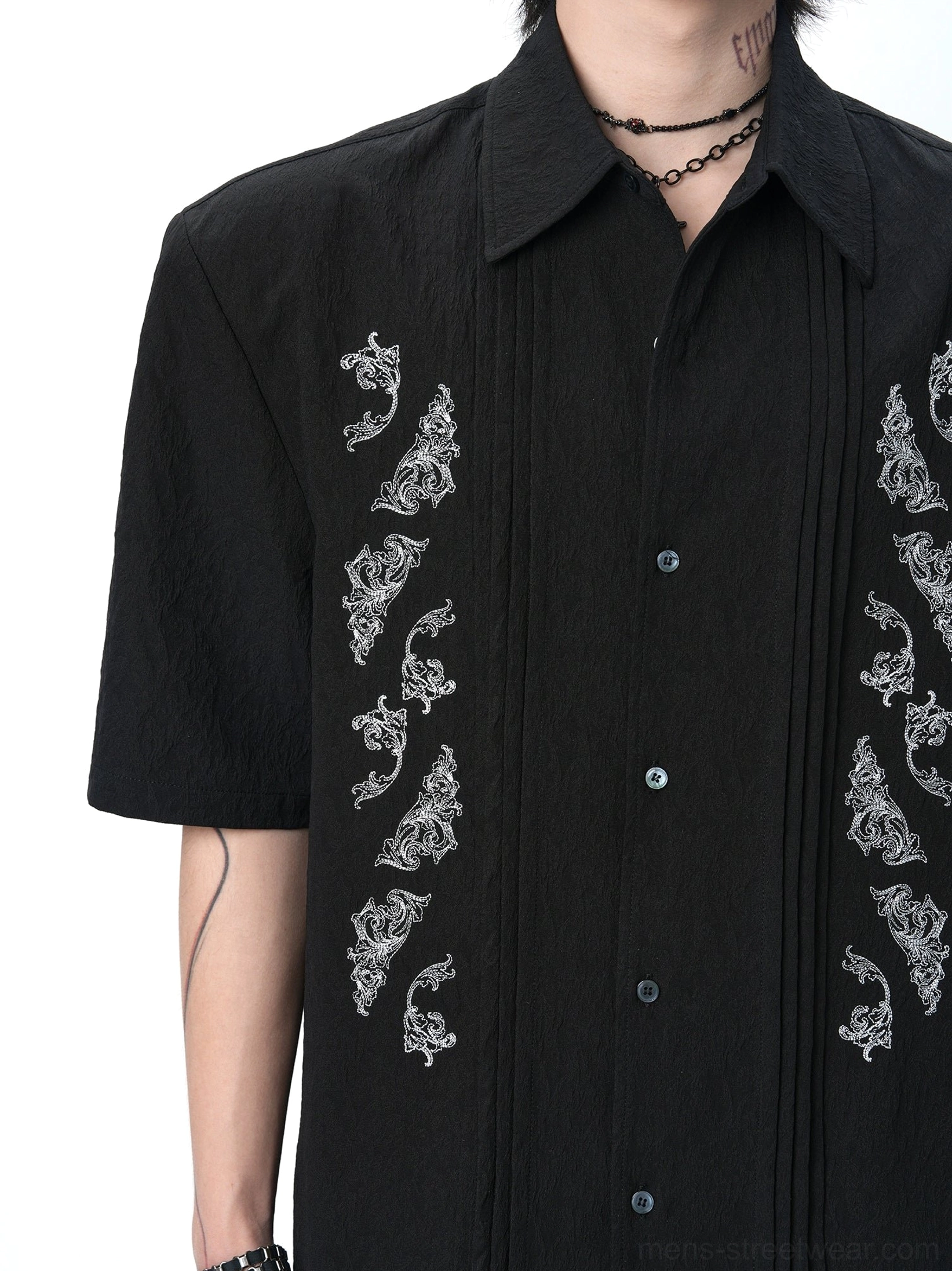 Close-up of black jacquard dragon embroidered Cuban shirt with pleated front panels pointed collar and matte buttons