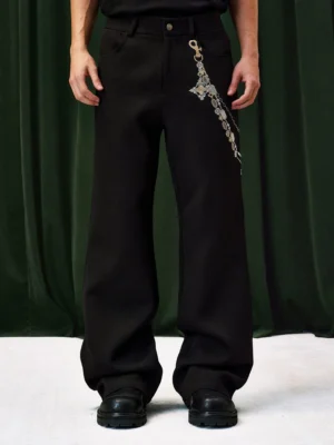 Front full-body view of black jeweled chain wide-leg streetwear pants with high waist, ornate gold-tone chain detail, and relaxed stacked silhouette