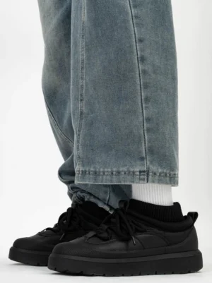 Black knit collar platform sneakers worn with baggy blue jeans and white socks, showing the chunky winter streetwear silhouette and ribbed ankle collar